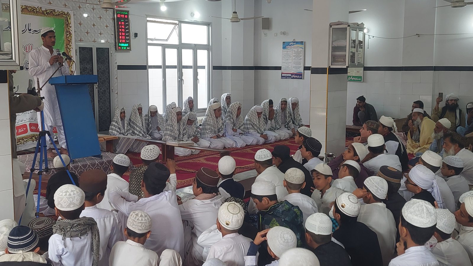 Student speaking during the Madrassa completion ceremony as attendees listen