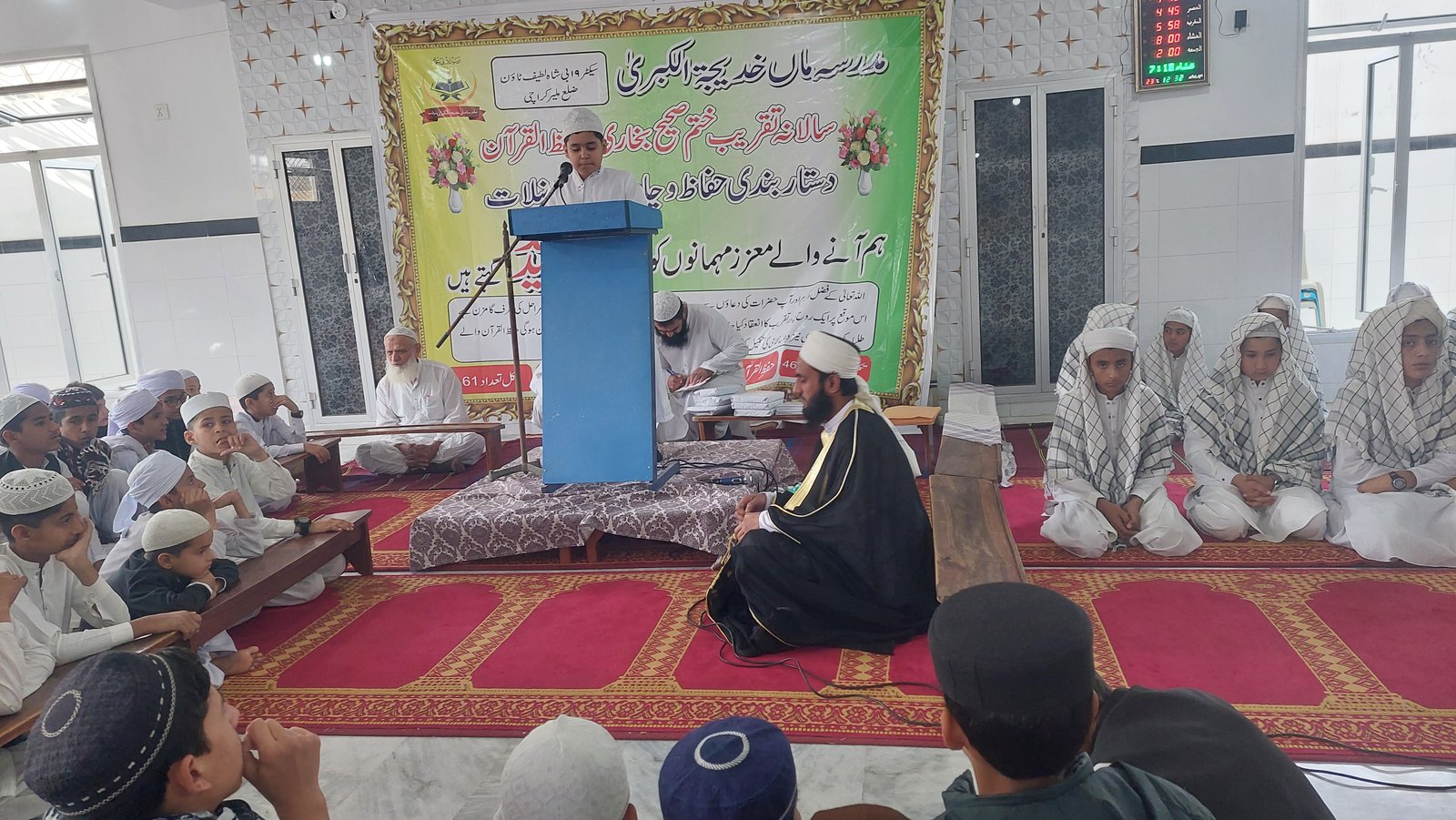Student speaking during a Quran completion ceremony at the Madrassa