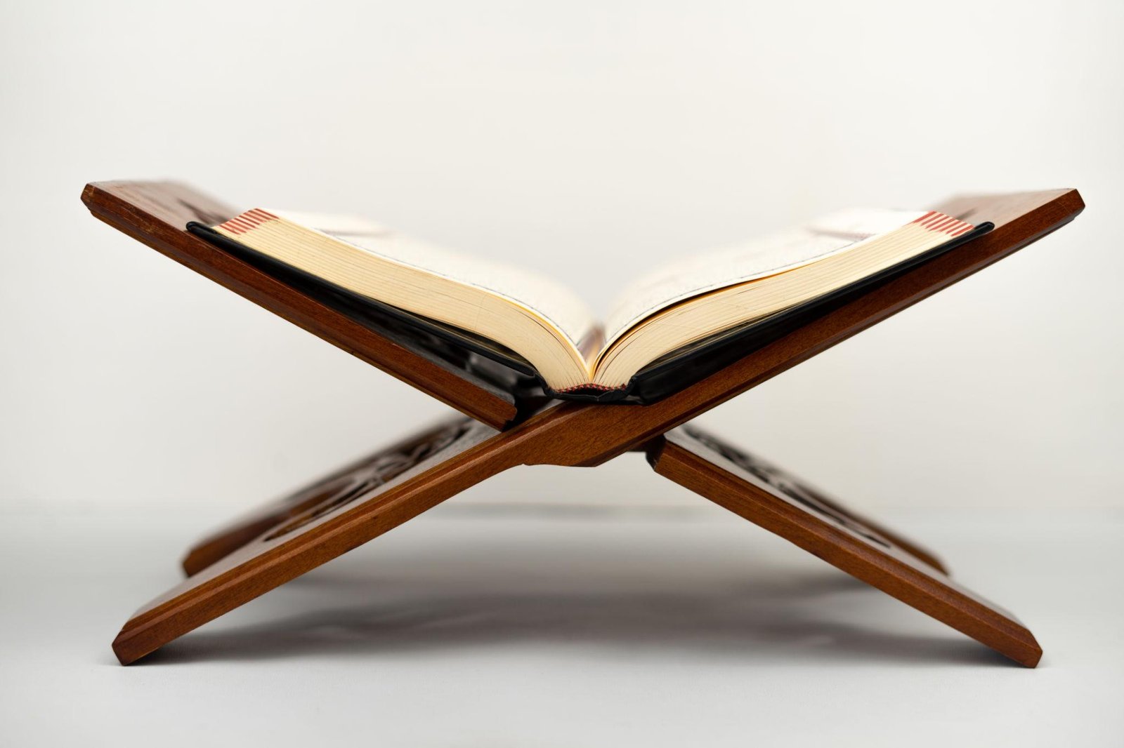 Open book resting on a wooden reading stand against a light background